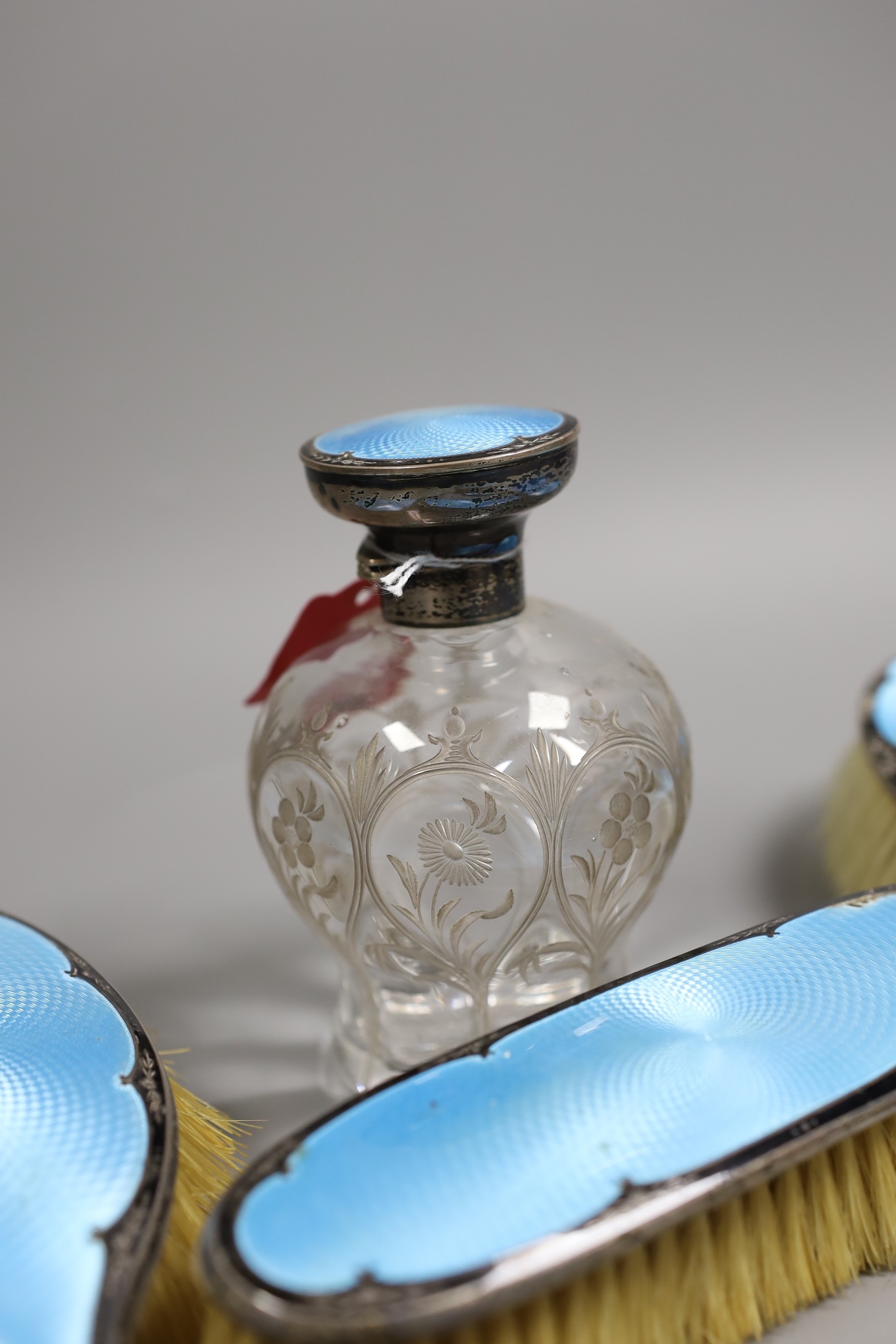A George V silver and two colour enamel mounted blue enamel mirror and brush set, including a scent bottle, (a.f.).